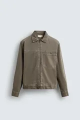 Sobrecamisa de denim de algodón negro con efecto lavado, corte relajado (relaxed fit). Presenta cuello solapa, cierre frontal con cremallera, manga larga con puño abotonado y bolsillo plastrón en el pecho.