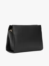 Cartera bandolera negra con textura granulada, correa ajustable y logo metálico dorado de Tommy Hilfiger en el frente.