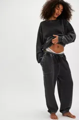 Pantalón de jogging negro con efecto gastado (acid wash) y costuras contrastantes claras. Presenta cintura con cordón ajustable y puños elásticos en los tobillos.