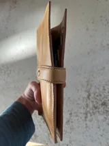 Portadocumentos de cuero color suela con cierre de cremallera y múltiples compartimentos para pasaportes, tarjetas y bolígrafo.