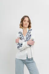 Camisa de manga larga en algodón liviano, color azul marino, con bordados florales en contraste en el frente y mangas. Cuello mao con terminación en ondas y puños fruncidos.