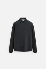 Camisa negra relaxed fit confeccionada en tejido fluido con mezcla de viscosa. Tiene cuello solapa, manga larga con puño abotonado y cierre frontal con botones.