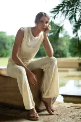 Pantalón largo color beige de tejido de punto con patrón floral, corte recto y cintura alta.