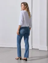 Blusa de algodón a rayas verticales finas en tonos blanco y lila, con escote en V, abertura frontal con botones y mangas largas regulables con presilla y botón. El ruedo termina anudado al frente.