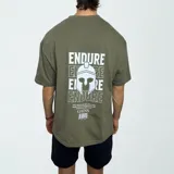 Remera verde militar de algodón con estampado en la espalda con la palabra "ENDURE" repetida y un casco espartano. Incluye una frase motivacional y el logo "GAINS."