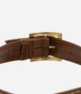 Sandalias planas marrones con tiras cruzadas y cierre con hebilla en el tobillo. Suela con efecto rafia.