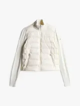 Chaleco acolchado color blanco con cuello alto, cierre frontal con cremallera, dos bolsillos laterales con cremallera y parche con logo en el pecho.