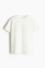 Remera blanca de algodón con cuello redondo y apliques de encaje en forma de círculos en el frente.