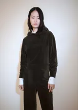 Buzo de pana color verde oscuro, de corte recto, con capucha y puños elásticos.