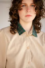 Vestido corto verde militar de microfibra con cuello camisero negro, cintura elastizada con cordón de ajuste y mangas cortas con dobladillo. Cierre frontal con botones.