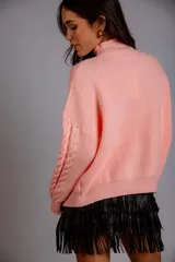 Sweater color crudo con cuello alto y diseño trenzado.
