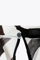 Top de cuello halter fluido y manga sisa con estampado de cebra en tonos marrones. Bajo asimétrico y cierre en el cuello con abertura y botón.