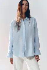 Camisa color ladrillo confeccionada en lino 100%, de corte recto, con cuello solapa, manga larga con puños y cierre frontal con botones.