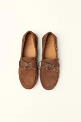 Mocasines náuticos de cuero color marrón, con cordones de cuero y suela de goma.