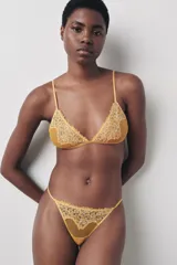 Tanga color ocre con cintura elástica fina y detalle de encaje floral en la parte delantera.