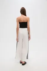 Pantalón blanco de viscosa, corte ancho y tiro alto, con detalle de bordado calado negro en los laterales.