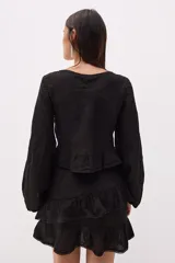 Top blanco de lino italiano con escote en V, mangas largas estilo globo y jareta ajustable en la parte delantera que crea un efecto fruncido y volado en el ruedo.