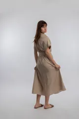 Vestido camisero midi color beige, con cuello camisero, mangas cortas con dobladillo, cierre frontal con botones y lazo para ajustar en la cintura.