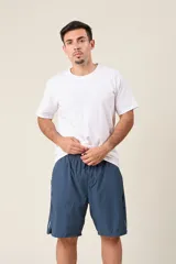 Bermuda deportiva de nylon color verde oliva, de corte suelto, con cintura elástica y cordón de ajuste. Cuenta con detalles de líneas verticales en los costados y bolsillos laterales con cierre.