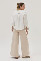 Camisa blanca de lino con bordados florales en tonos beige y azul.