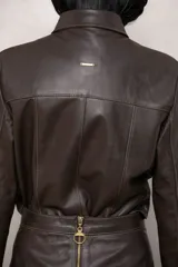 Camisa de cuero marrón con cuello clásico, botones metálicos al frente y volados de gamuza al tono en el pecho y puños.