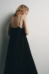 Vestido midi negro de tejido plisado, con escote pico, tirantes finos ajustables y aplicación de encaje y bordados florales combinados a contraste.