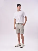 Bermuda color gris con cintura elástica ajustable con cordón, bolsillos laterales y un bolsillo tipo cargo en la pierna izquierda.
