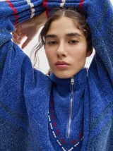 Sweater azul con cuello alto con medio cierre, textura tipo terciopelo y puños acanalados.