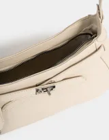 Bandolera de cuerina color gris claro, con correa de hombro ajustable, cinturón frontal decorativo y charm lateral con forma de mariquita.