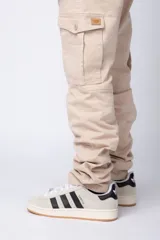 Pantalón cargo color beige con bolsillos laterales con solapa y botón. Corte ajustado.