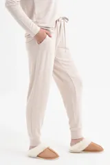 Conjunto de pantalón y remera de mangas largas color beige, de corte holgado. El pantalón tiene cintura elástica con cordón ajustable y bolsillos laterales.