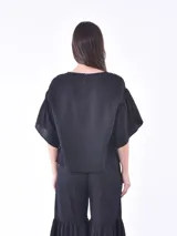 Blusa negra de mangas cortas con volados y escote redondo.