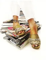 Sandalia beige con detalle de plumas en la tira delantera y taco chato.