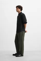 Pantalón verde oscuro con textura de rayas verticales, corte relaxed fit, cintura elástica ajustable con cordón, bolsillos delanteros y bolsillo trasero de parche.