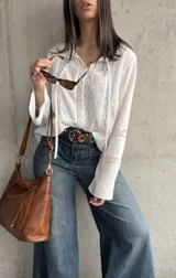 Blusa blanca de manga larga con detalles de encaje en el frente, mangas y cuello.