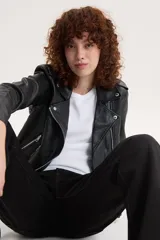Campera biker negra de cuero sintético con cuello solapa, cierre cruzado con cremallera, bolsillos con cremallera y cinturón ajustable.