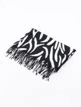 Bufanda rectangular de tejido suave con estampado de cebra en blanco y negro y flecos en los extremos.