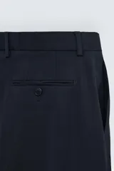 Pantalón de vestir azul marino, de corte recto, con bolsillos laterales y traseros. Se ajusta a la cintura con cinturón de cuero marrón.