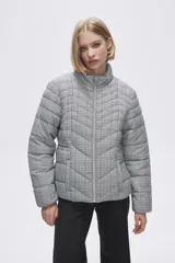 Campera puffer estampada a cuadros en blanco y negro con pequeños corazones rosados, cierre frontal con cremallera y bolsillos laterales.