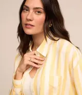 Camisa de viscolino con estampado de rayas verticales amarillas y blancas, corte alargado, cuello inglés, mangas largas y bolsillo en el pecho.