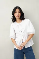 Blusa blanca de algodón con mangas abullonadas, escote redondo y lazos frontales.