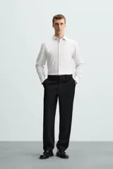 Camisa celeste a rayas verticales blancas, de corte recto, con cuello italiano abierto, mangas largas con puños abotonados y cierre frontal con botones.