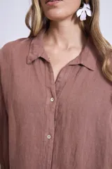 Camisa de lino color terracota, con cuello camisero, botones frontales y mangas amplias de tres cuartos.
