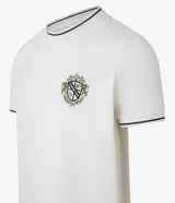 Remera de algodón y poliéster color crudo, con cuello redondo y manga corta. Presenta textura acanalada horizontal, estampa localizada con escudo y ribetes en contraste en cuello y mangas.