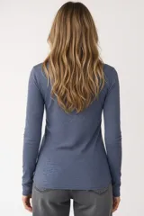 Remera de manga larga entallada en color blanco, confeccionada en algodón. Presenta cuello redondo con una hilera de botones frontales y un pequeño bolsillo en el pecho con detalle de botón.