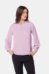 Blusa de manga larga blanca con botones forrados en el pecho y doble capa en el frente.