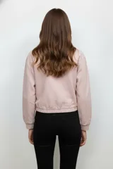 Campera corta color beige, estilo bomber, de manga larga y cierre frontal con cremallera. Tiene dos bolsillos con solapa en el pecho.