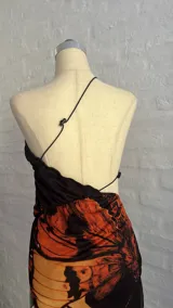 Minivestido con estampado de mariposas en tonos naranja y negro, con escote halter asimétrico y abertura en la cintura.