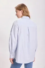 Camisa celeste con hombreras y mangas abullonadas.