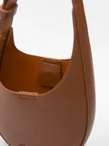 Bandolera pequeña color tostado, con textura granulada, un compartimento y cierre magnético. Tiene asa larga regulable y logo grabado.